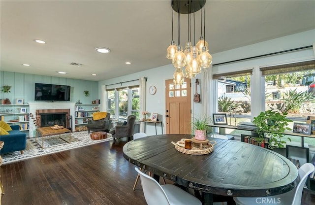 dining room with wood-type flooring and a brick fireplace