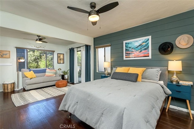 bedroom featuring ceiling fan, dark hardwood / wood-style flooring, and wood walls