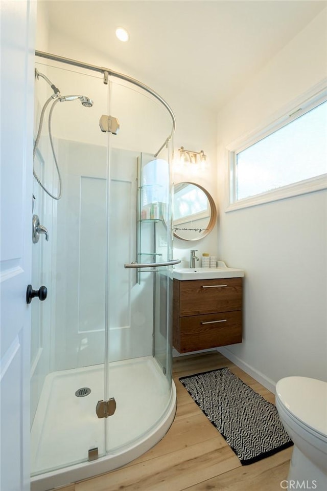 bathroom with hardwood / wood-style flooring, vanity, toilet, and a shower with shower door