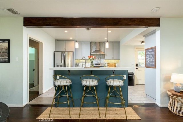 kitchen with gray cabinetry, backsplash, wall chimney range hood, dark hardwood / wood-style floors, and stainless steel refrigerator