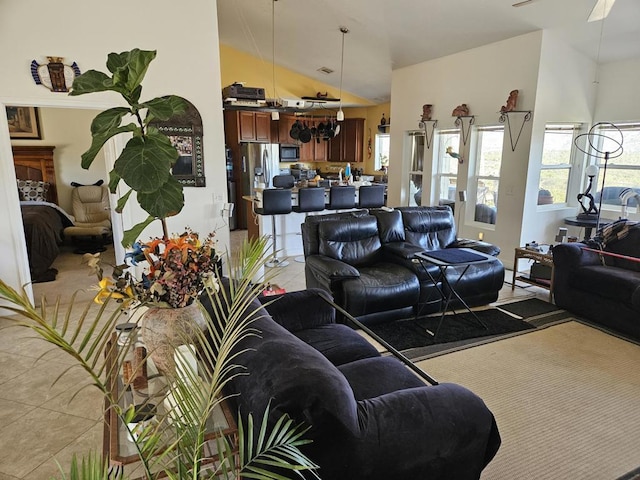 tiled living room featuring ceiling fan and vaulted ceiling