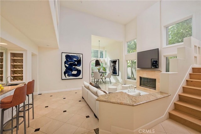 living room with light tile patterned flooring, a towering ceiling, a fireplace, and a wealth of natural light