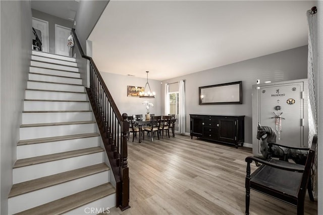 staircase featuring hardwood / wood-style flooring and an inviting chandelier