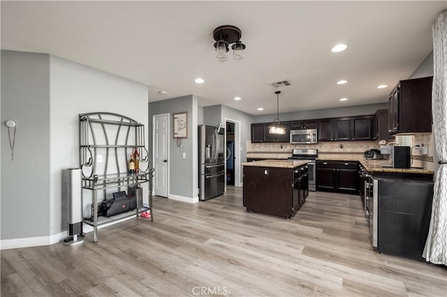 kitchen featuring a center island, stainless steel appliances, tasteful backsplash, light hardwood / wood-style floors, and decorative light fixtures