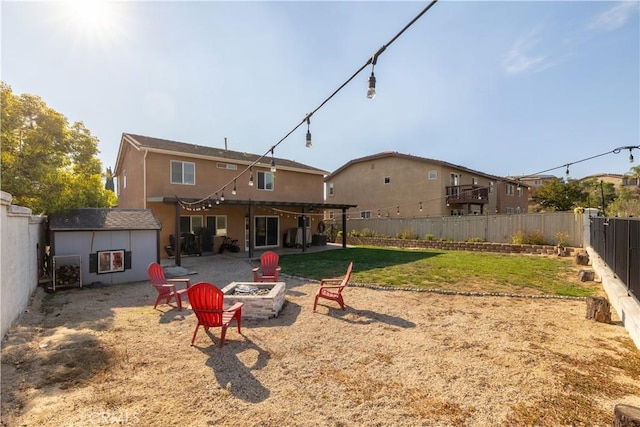 rear view of house with a patio area, a yard, and a fire pit