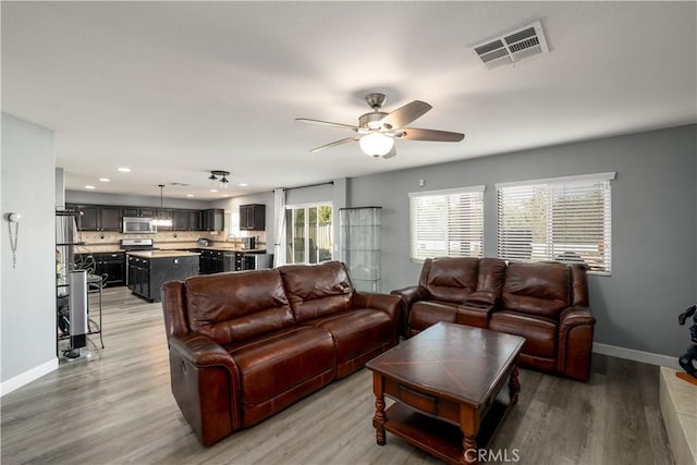 living room with ceiling fan, sink, and hardwood / wood-style flooring