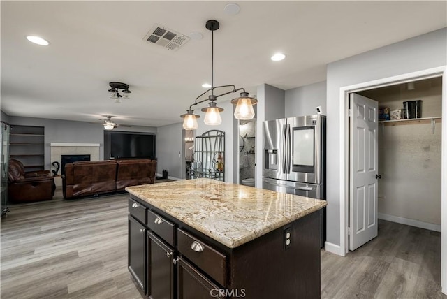 kitchen with ceiling fan, a center island, hanging light fixtures, stainless steel fridge with ice dispenser, and light wood-type flooring