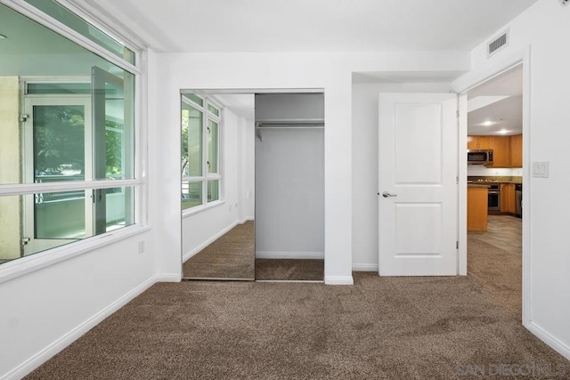 unfurnished bedroom featuring dark carpet and a closet