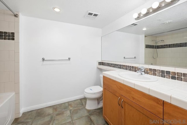 full bathroom with tiled shower / bath combo, tasteful backsplash, tile patterned floors, toilet, and vanity