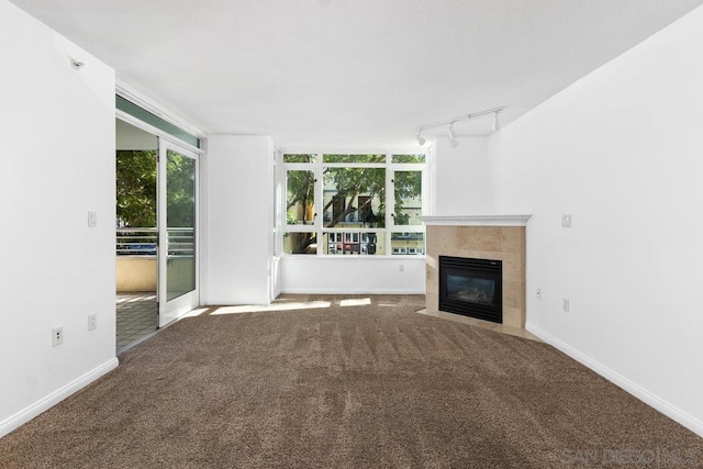 unfurnished living room featuring carpet, a wealth of natural light, and track lighting