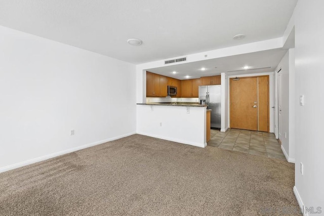 kitchen with a kitchen bar, kitchen peninsula, stainless steel appliances, and light carpet