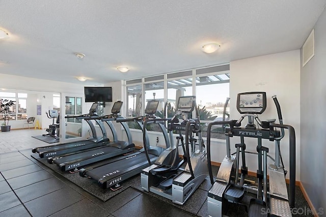 gym with a textured ceiling and a healthy amount of sunlight