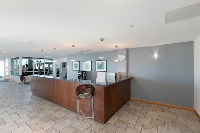 interior space with a kitchen breakfast bar, kitchen peninsula, dark stone counters, and pendant lighting