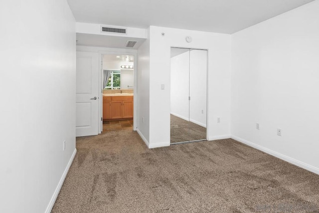 unfurnished bedroom with carpet flooring, a closet, and sink