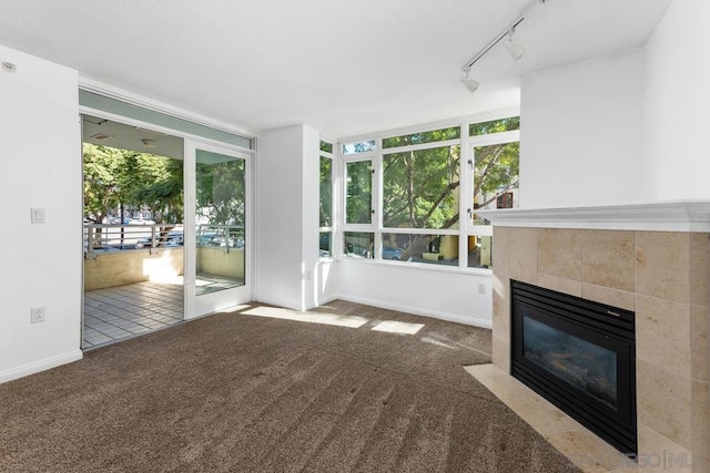 unfurnished living room featuring a fireplace, light colored carpet, and rail lighting