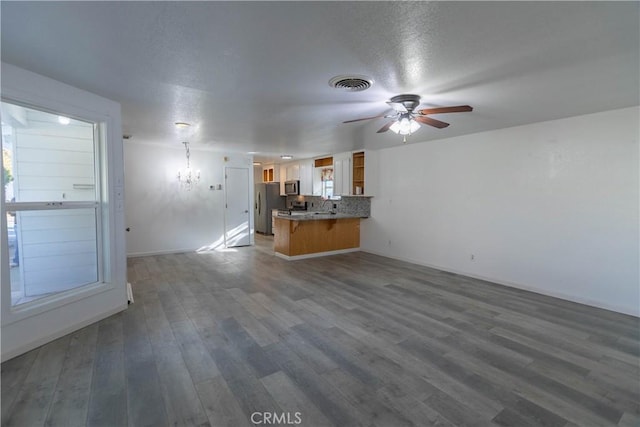 unfurnished living room with ceiling fan with notable chandelier, dark wood-type flooring, and sink