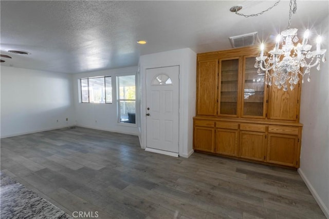 entryway with dark hardwood / wood-style flooring, a textured ceiling, and a notable chandelier