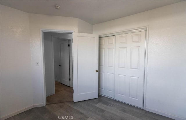 unfurnished bedroom featuring a closet and dark wood-type flooring