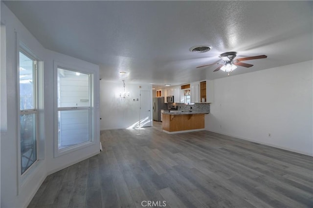 unfurnished living room featuring ceiling fan with notable chandelier, dark hardwood / wood-style floors, and sink