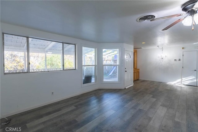 unfurnished room with ceiling fan with notable chandelier and dark hardwood / wood-style floors