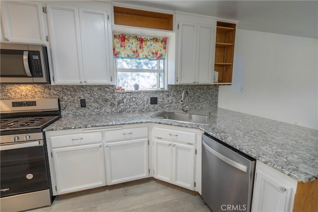 kitchen featuring sink, kitchen peninsula, decorative backsplash, white cabinets, and appliances with stainless steel finishes