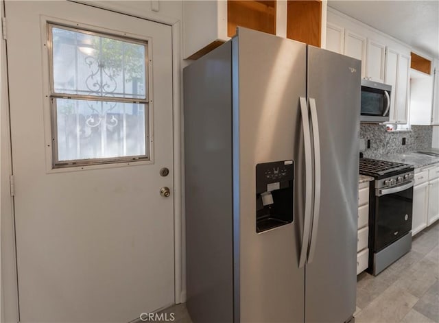 kitchen featuring decorative backsplash, white cabinets, light stone countertops, and appliances with stainless steel finishes