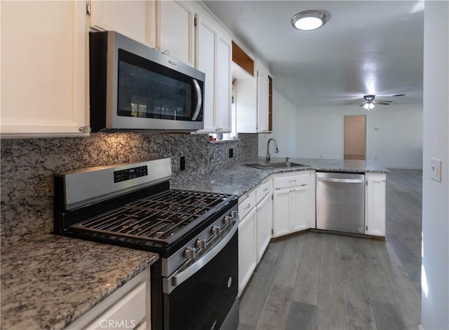 kitchen featuring white cabinets, stainless steel appliances, light stone counters, and sink