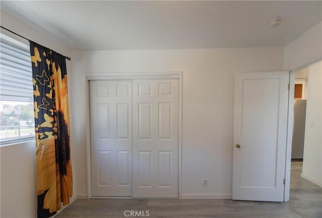 unfurnished bedroom with light wood-type flooring and a closet