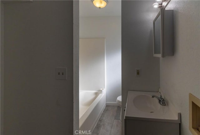 bathroom with toilet, vanity, a bath, and hardwood / wood-style flooring