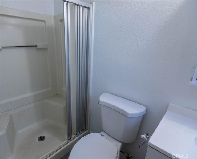 bathroom featuring vanity, toilet, and a shower with shower door