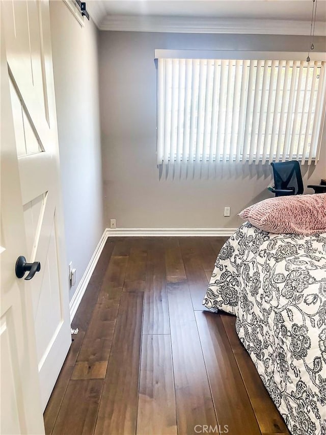 bedroom with crown molding, a barn door, and dark hardwood / wood-style floors