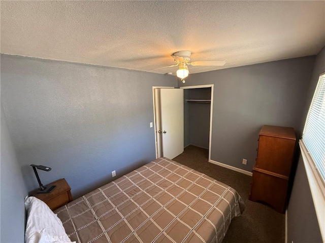 bedroom with ceiling fan, dark carpet, a textured ceiling, and a closet