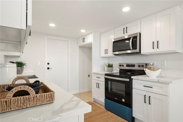 kitchen with light hardwood / wood-style floors, light stone counters, white cabinetry, and stainless steel appliances