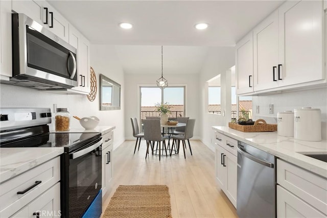 kitchen featuring light stone countertops, appliances with stainless steel finishes, light wood-type flooring, pendant lighting, and white cabinets