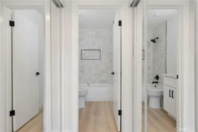 full bathroom featuring hardwood / wood-style flooring, vanity, toilet, and tiled shower / bath