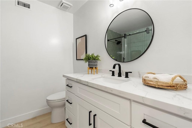 bathroom featuring vanity, toilet, wood-type flooring, and a shower with door