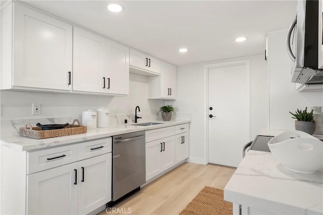 kitchen with white cabinets, light hardwood / wood-style floors, stainless steel dishwasher, and sink