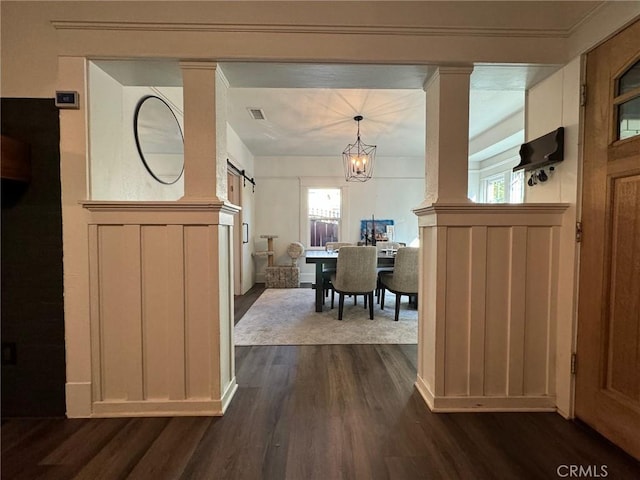 entryway featuring plenty of natural light, a barn door, a decorative wall, and dark wood-style floors