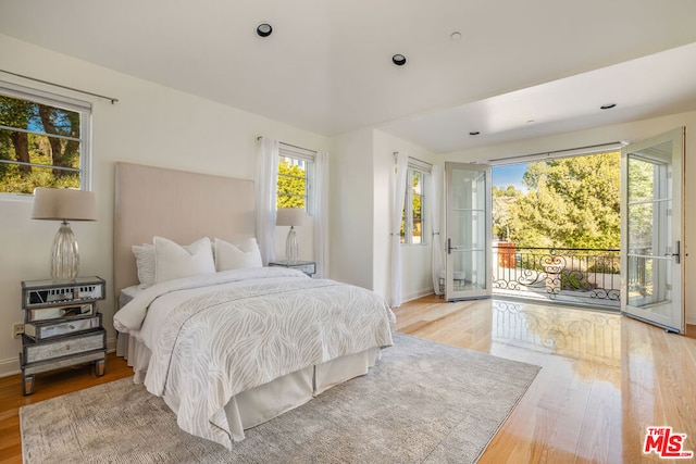 bedroom featuring multiple windows, access to exterior, and light hardwood / wood-style flooring