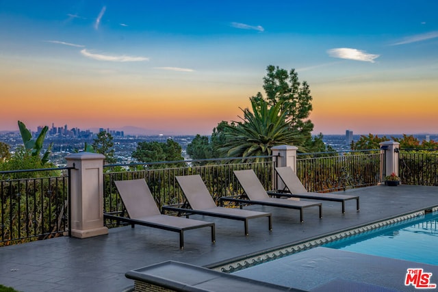 pool at dusk featuring a patio area