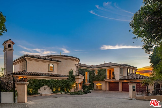 mediterranean / spanish-style home featuring a garage and a balcony