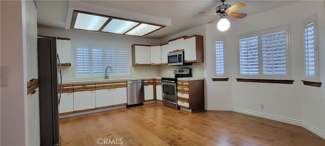 kitchen with tasteful backsplash, light hardwood / wood-style floors, stainless steel appliances, and white cabinetry