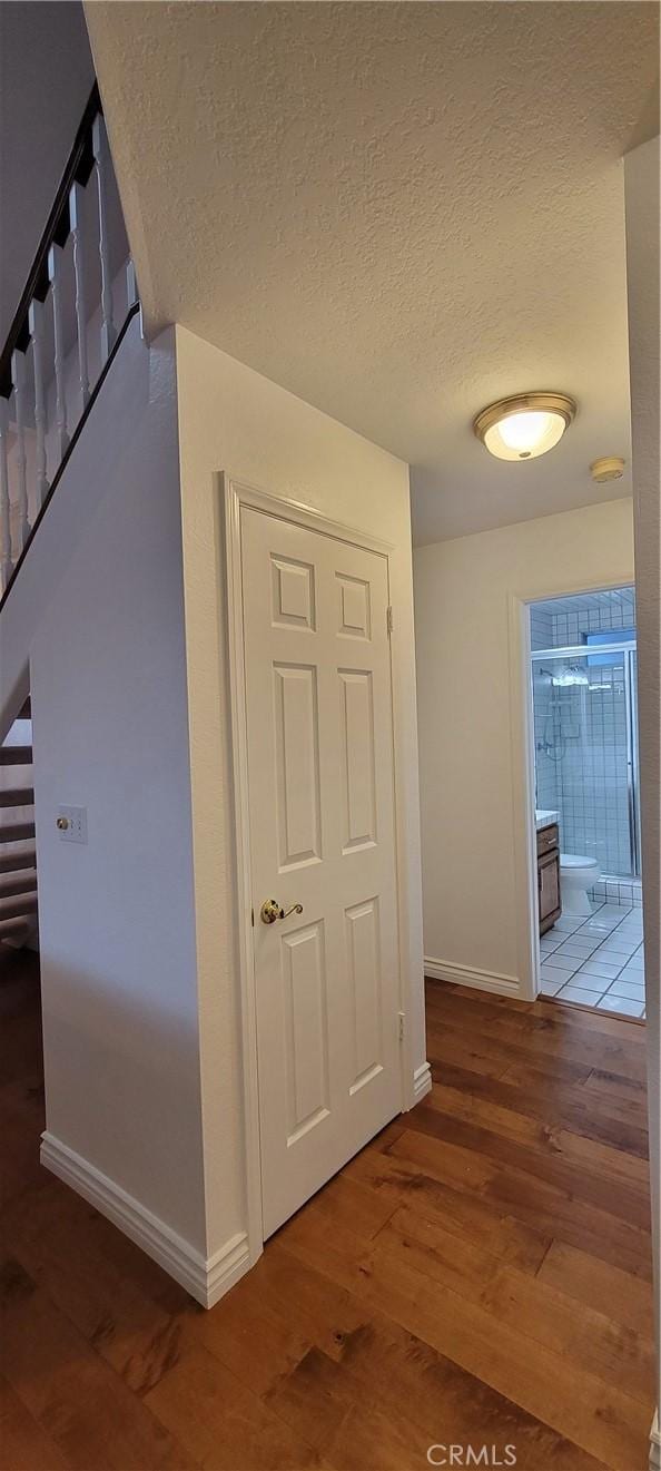 corridor with a textured ceiling and dark hardwood / wood-style floors