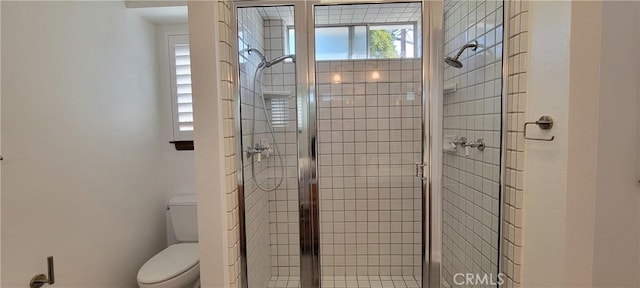 bathroom featuring toilet and a shower with door