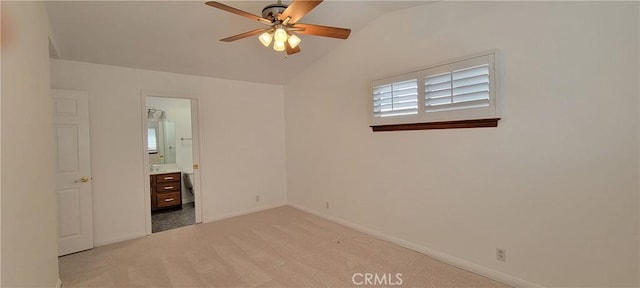 unfurnished bedroom featuring ceiling fan, ensuite bathroom, light carpet, and vaulted ceiling