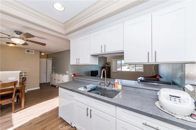 kitchen featuring white dishwasher, crown molding, sink, light hardwood / wood-style flooring, and white cabinetry