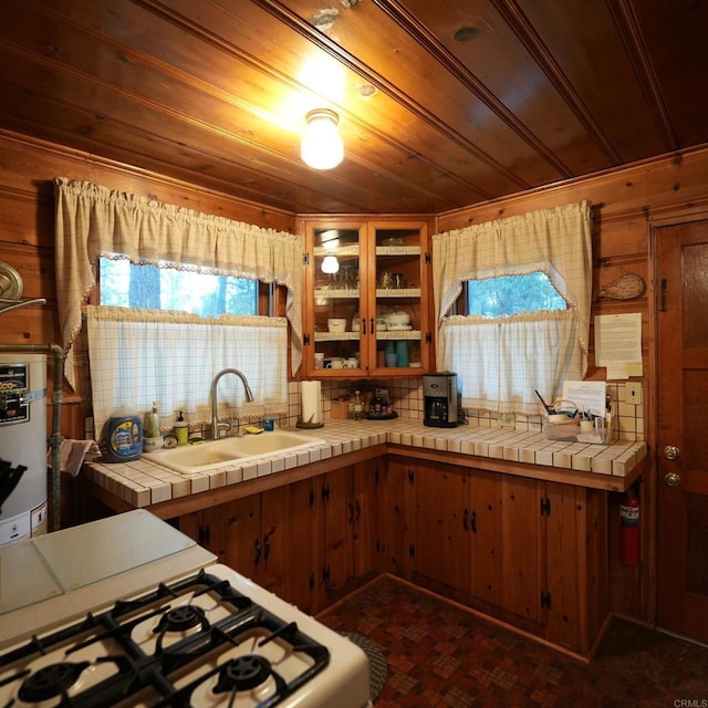 kitchen featuring tile countertops, sink, wooden walls, decorative backsplash, and white gas stove