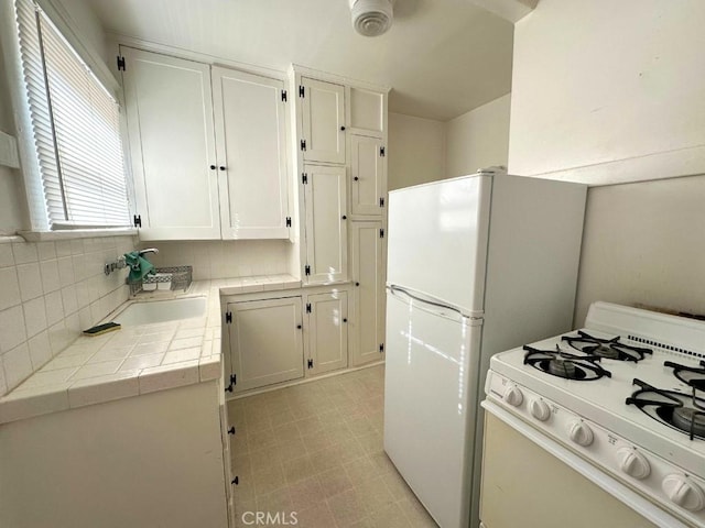 kitchen featuring tile countertops, white appliances, backsplash, sink, and white cabinetry