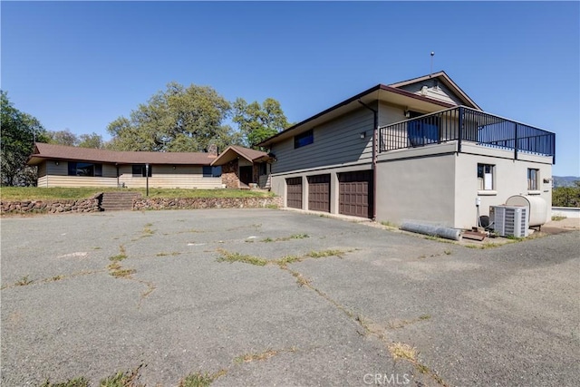 view of home's exterior with a garage, a balcony, and central AC