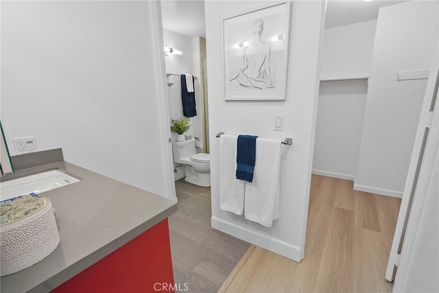 bathroom with hardwood / wood-style floors, vanity, toilet, and a textured ceiling